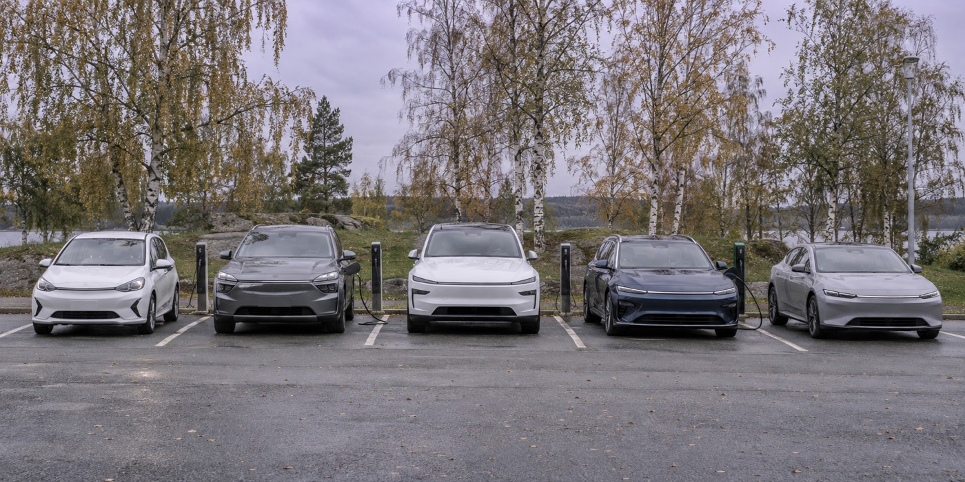 Rad med olika moderna elbilar parkerade på en parkering i dagsljus