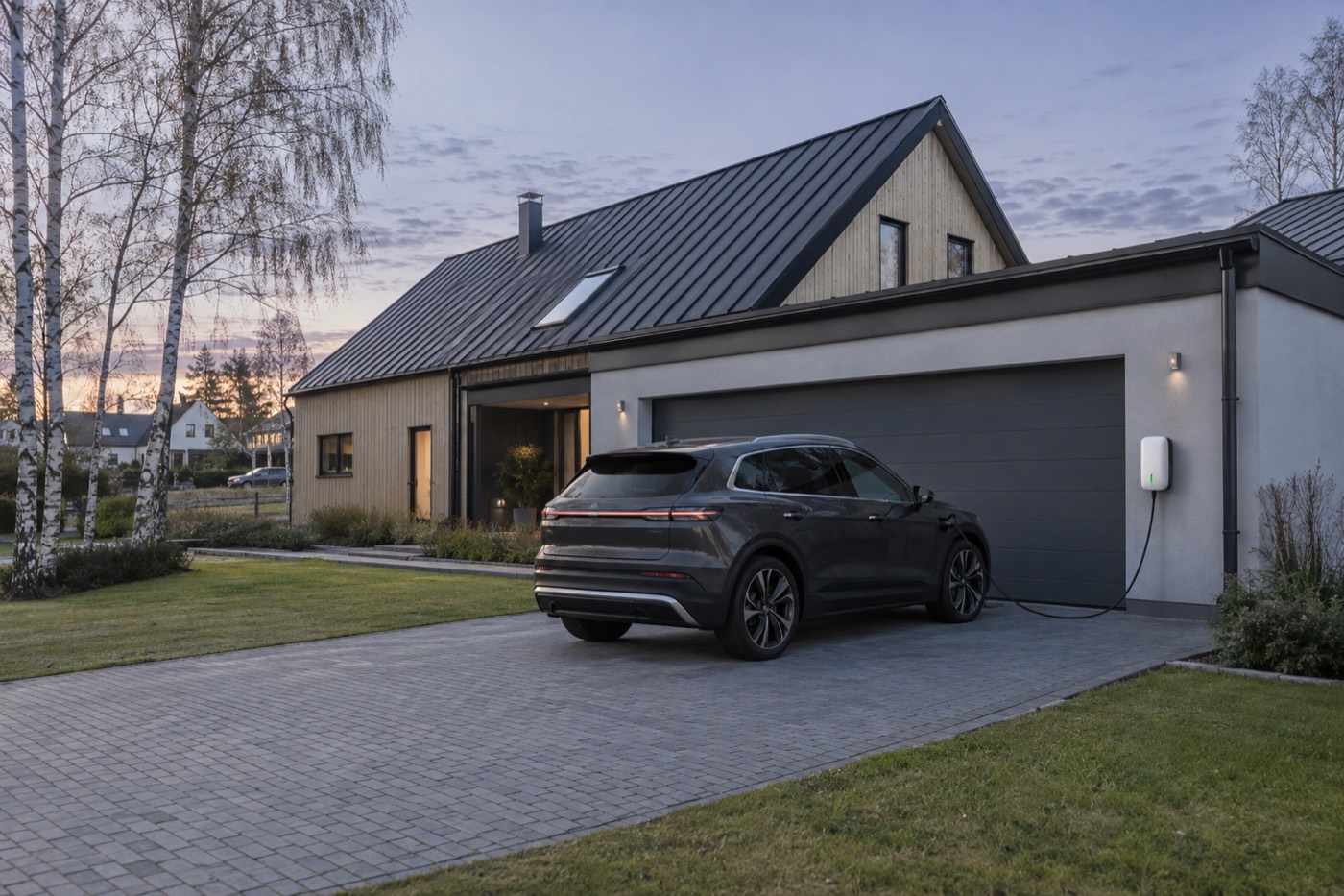 Elbil laddar från en väggmonterad laddbox vid garaget till en svensk villa
