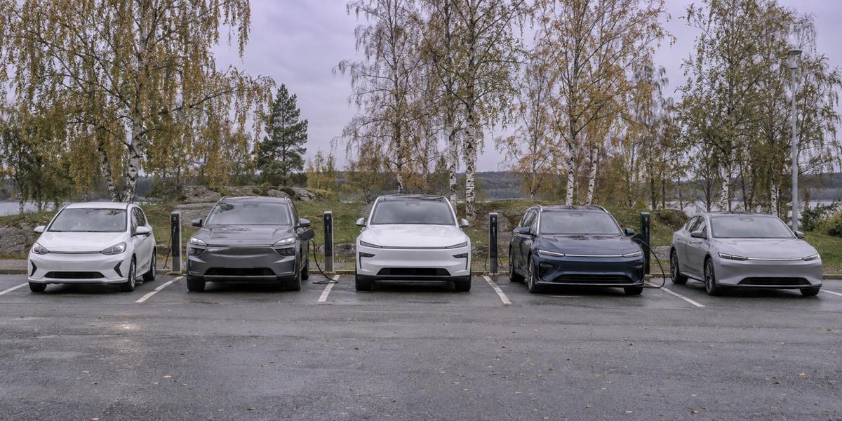 Rad med olika moderna elbilar parkerade på en parkering i dagsljus